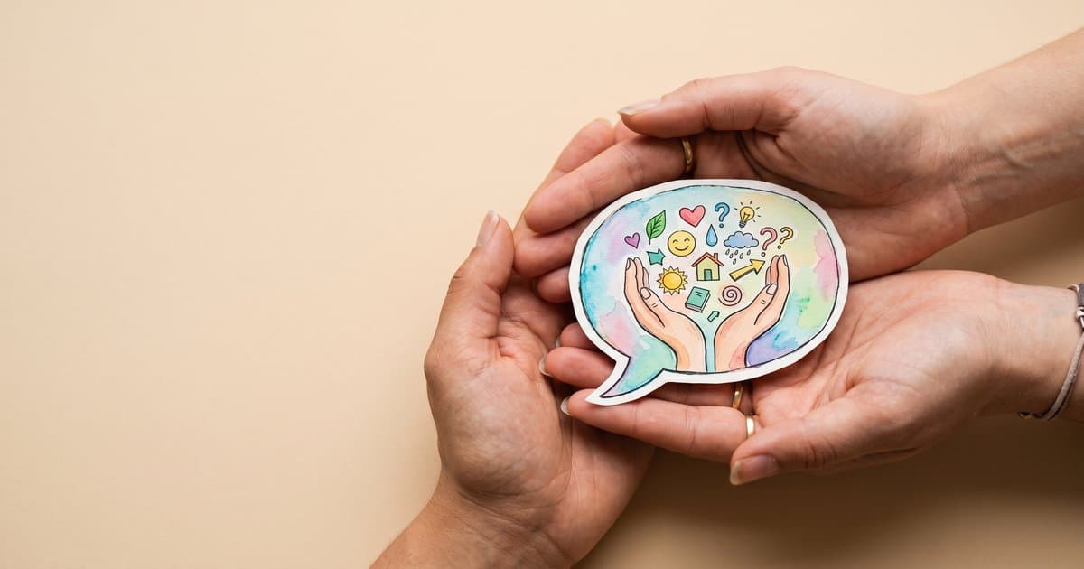 Hands cradling a colourful speech bubble that represents behaviour as a form of communication