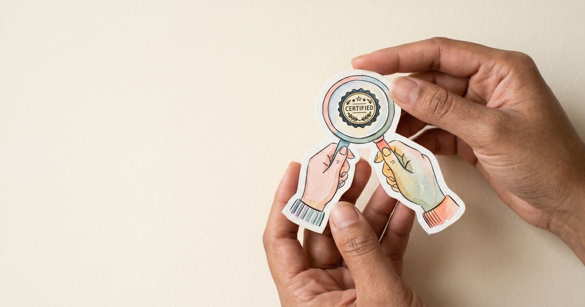 Hands holding a magnifying glass examining a BILD Act certification seal