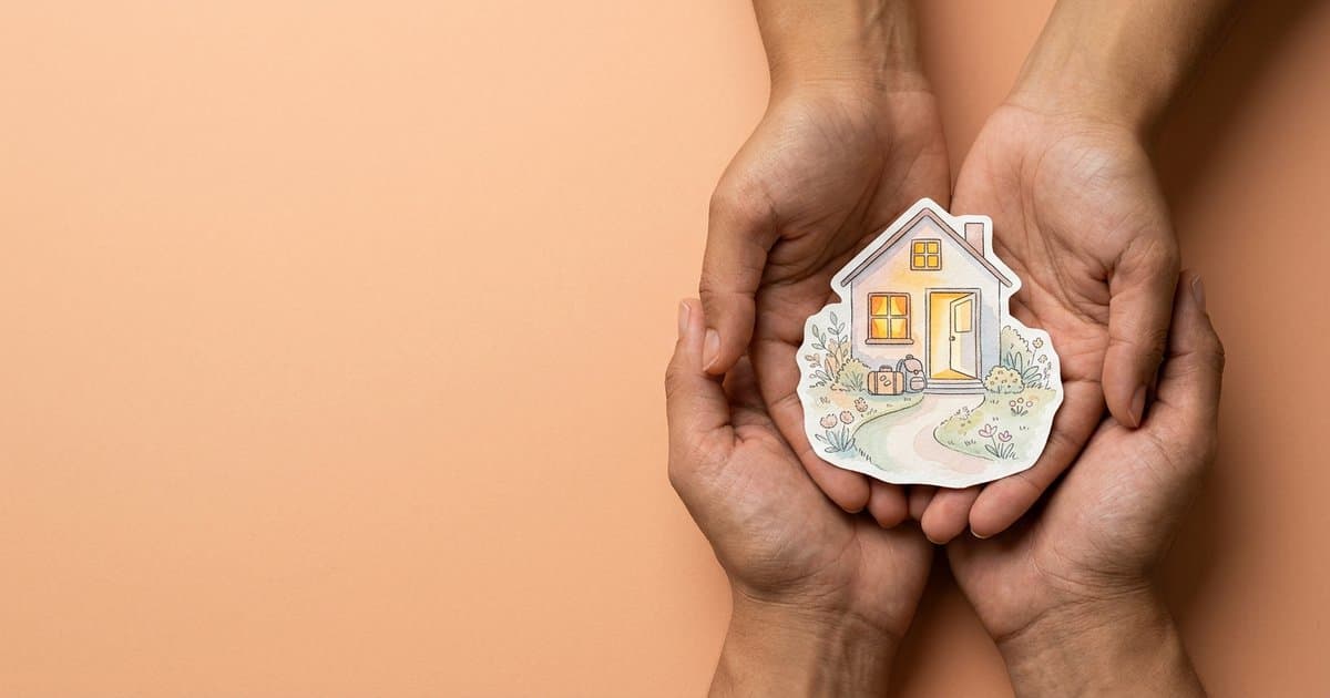 Two hands cradling a watercolour paper house with a glowing window, an open door and a small suitcase waiting on the doorstep