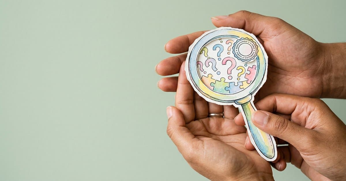 Photo of hands holding a watercolour magnifying glass with question marks and puzzle pieces, representing practical strategies for teaching critical thinking skills.